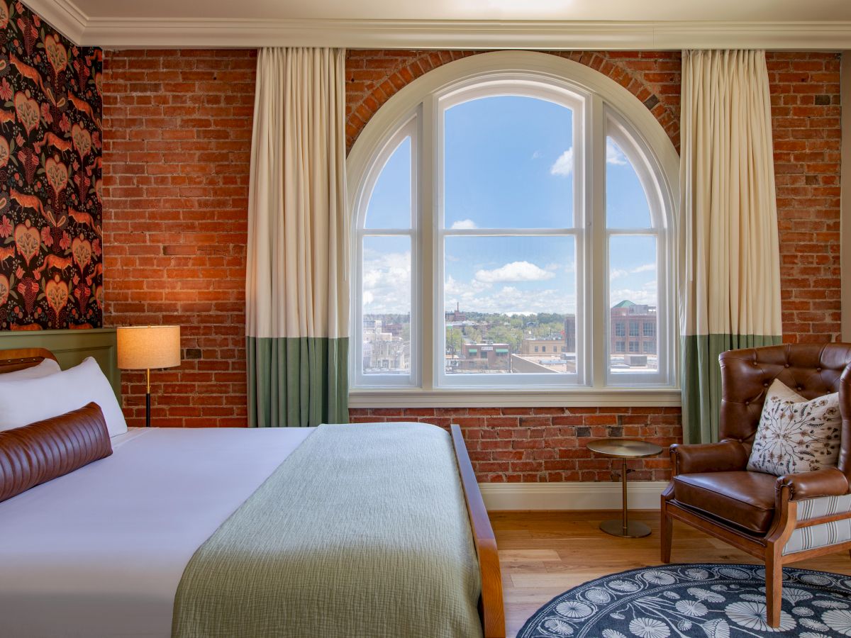A cozy bedroom with a patterned wallpaper, plush bedding, and a picture window