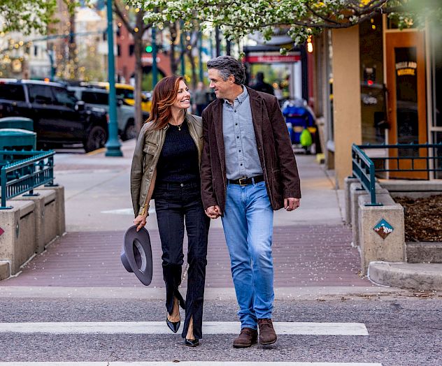 Two people are walking across a street together.
