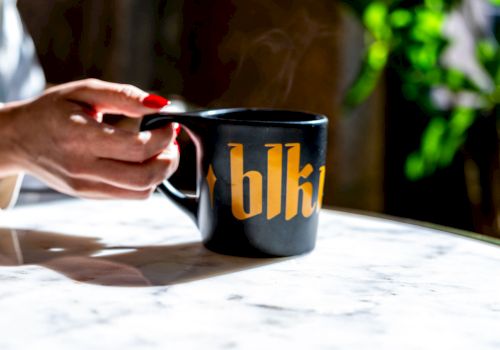A hand holding a black mug with 