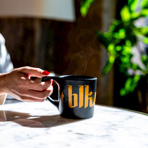 A hand holding a black mug with 