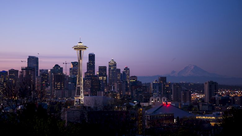 This image shows the Seattle skyline at dusk, with the Space Needle prominently visible and Mount Rainier in the background.